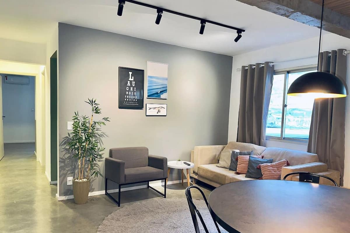 Una sala de estar moderna con un sofá, un sillón, una mesa de comedor y una planta en maceta.