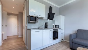 A modern kitchen with white cabinets, a microwave, a coffee maker, and an oven. - 4 Star Holiday Home in Travemunde (Lübeck)