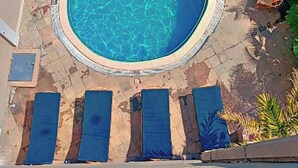 Una piscina con due zone separate, circondata da sdraio e un’area lounge coperta.