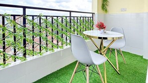 Un balcón con césped artificial, una mesa con dos sillas y vistas a la ciudad.