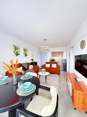 A modern living room with a dining area, a kitchen in the background, and a TV mounted on the wall. - Welcome to this cosy 2 bedroom apartment located 5 minutes to nairobi cbd (Nairobi)