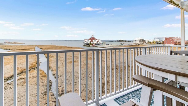 Een balkon met uitzicht op het strand en een vuurtoren.