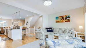 A spacious living area with a sofa, a dining table, and a kitchen in the background. - Broadmarsh 115C (Ocean City)