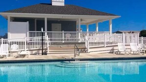 A pool with a white fence, lounge chairs, and a covered area with steps leading to a door. - Broadmarsh 115C (Ocean City)