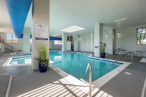 Ein Hallenbad mit Übersicht der Badregeln, einer blauen Decke und einer Sitzgelegenheit mit Stühlen und Tisch.