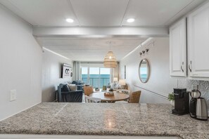 Eine moderne Küche mit Granit-Arbeitsplatten, einer Kaffeemaschine und einem Essbereich mit rundem Tisch und Stühlen.