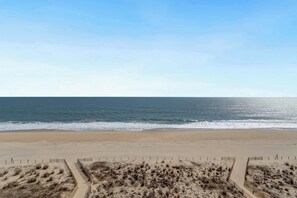 Ein Strand mit sandigem Ufer, einer Holzumzäunung und blauem Himmel.
