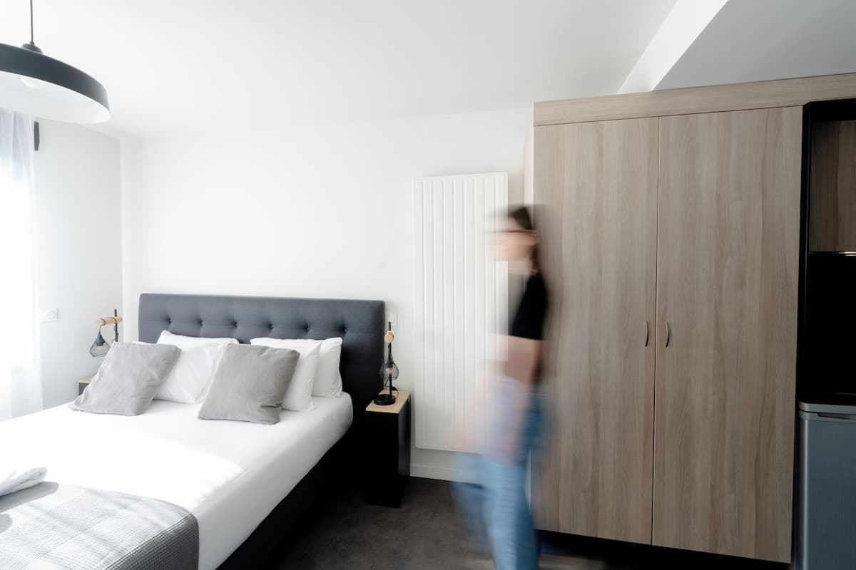 A modern bedroom with a bed, bedside tables, a wardrobe, and a hanging light fixture.