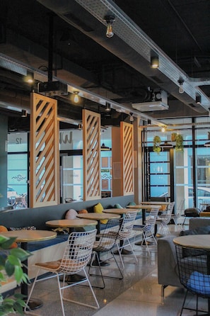 A modern indoor space with seating areas, tables, and hanging plants. - Slo Appart Hotel Bordeaux - Cité du Vin (Bordeaux)