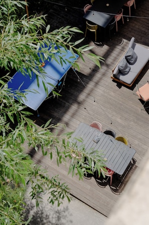 A deck with outdoor furniture, including a table and chairs, surrounded by greenery. - Slo Appart Hotel Bordeaux - Cité du Vin (Bordeaux)