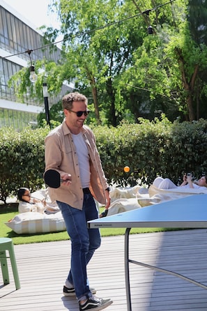 A person playing table tennis outdoors with a table and net. - Slo Appart Hotel Bordeaux - Cité du Vin (Bordeaux)