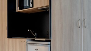 Una cocina moderna con armarios de madera, microondas integrado y refrigerador de acero inoxidable.