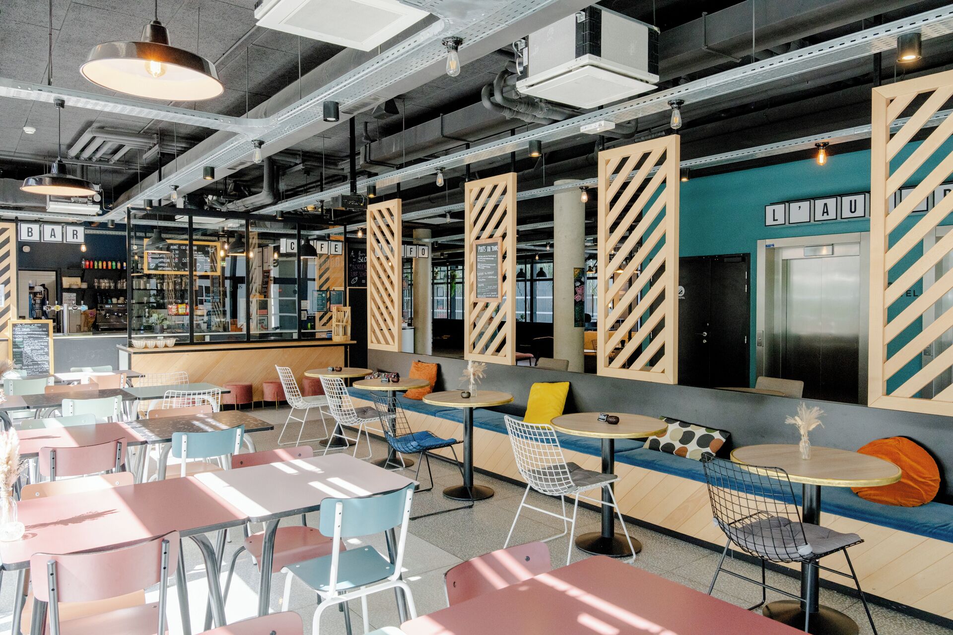 A modern cafe with seating areas, tables, and a bar.