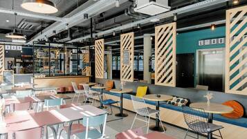 A modern cafe with seating areas, tables, and a bar.