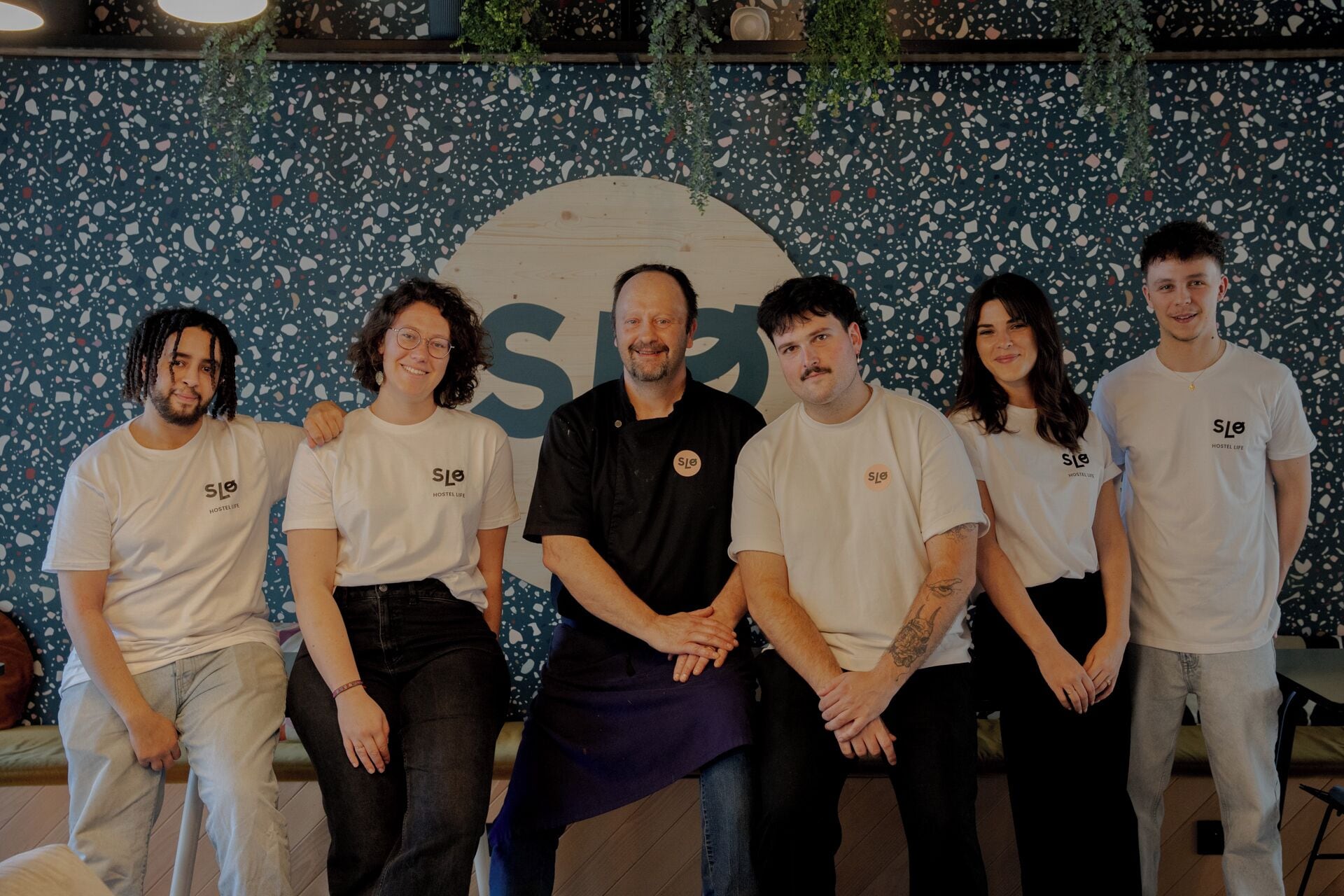 A group of people standing in front of a wall with a large logo.