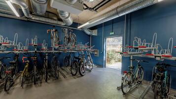 Een fietsverhuurstation met meerdere fietsen en fietsenrekken, een betonnen vloer en een blauwe muur.