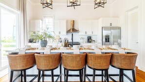 A modern kitchen with white cabinets, a central island with bar stools, and pendant lighting. - Villa Ya Huru & Mistico Beach Club + Boat Shuttle (San Pedro)
