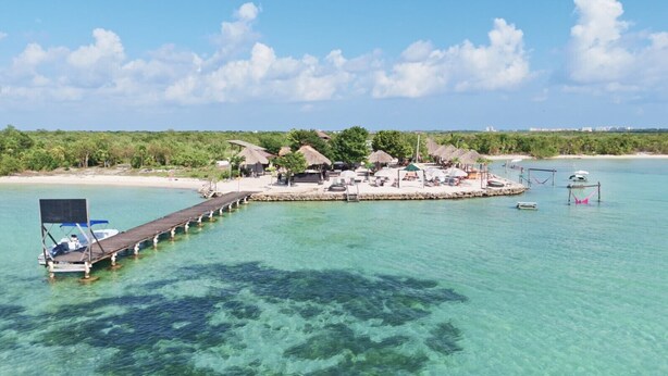 A resort with a pier extending into clear turquoise waters, surrounded by lush greenery and thatched-roof structures. - Villa Ya Huru & Mistico Beach Club + Boat Shuttle (San Pedro)