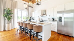 A modern kitchen with a central island, bar stools, stainless steel appliances, and a large potted plant. - Villa Ya Huru & Mistico Beach Club + Boat Shuttle (San Pedro)