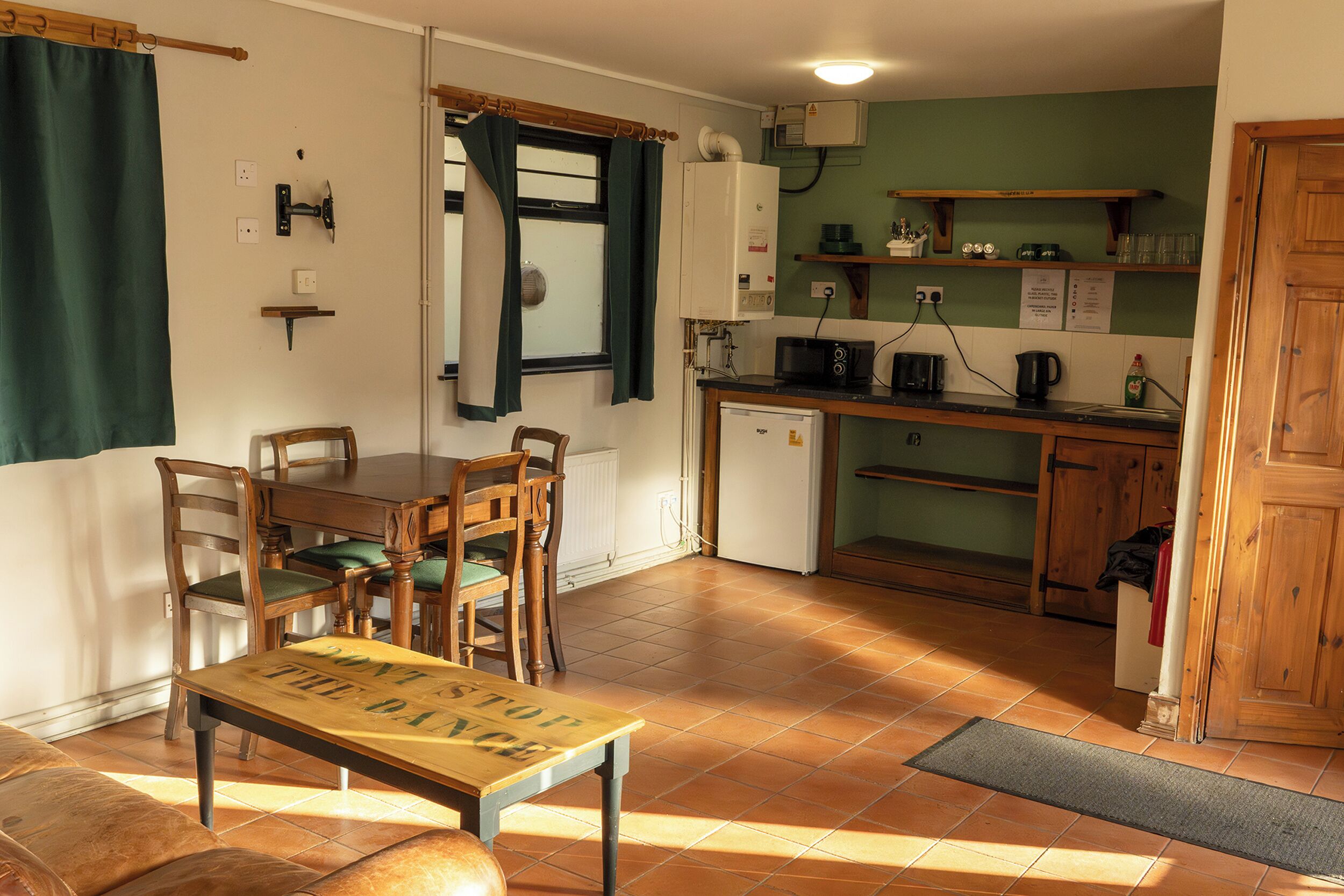 A compact kitchen with a dining area, a small refrigerator, and a wooden cabinet.