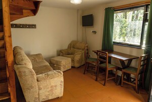 Una sala de estar con sofá, sillón, mesa de comedor y sillas.