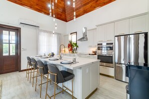 A modern kitchen with a central island, stainless steel appliances, and a wooden ceiling. - Abebi Oasis & Mistico Beach Club + Boat Shuttle (San Pedro)