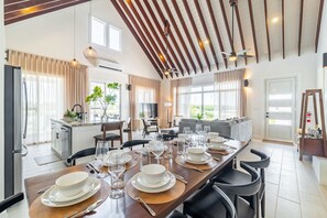 Eine moderne Küche mit Essbereich, gedeckt für eine Mahlzeit, inklusive langem Tisch, Stühlen und einem Fernseher im Hintergrund.