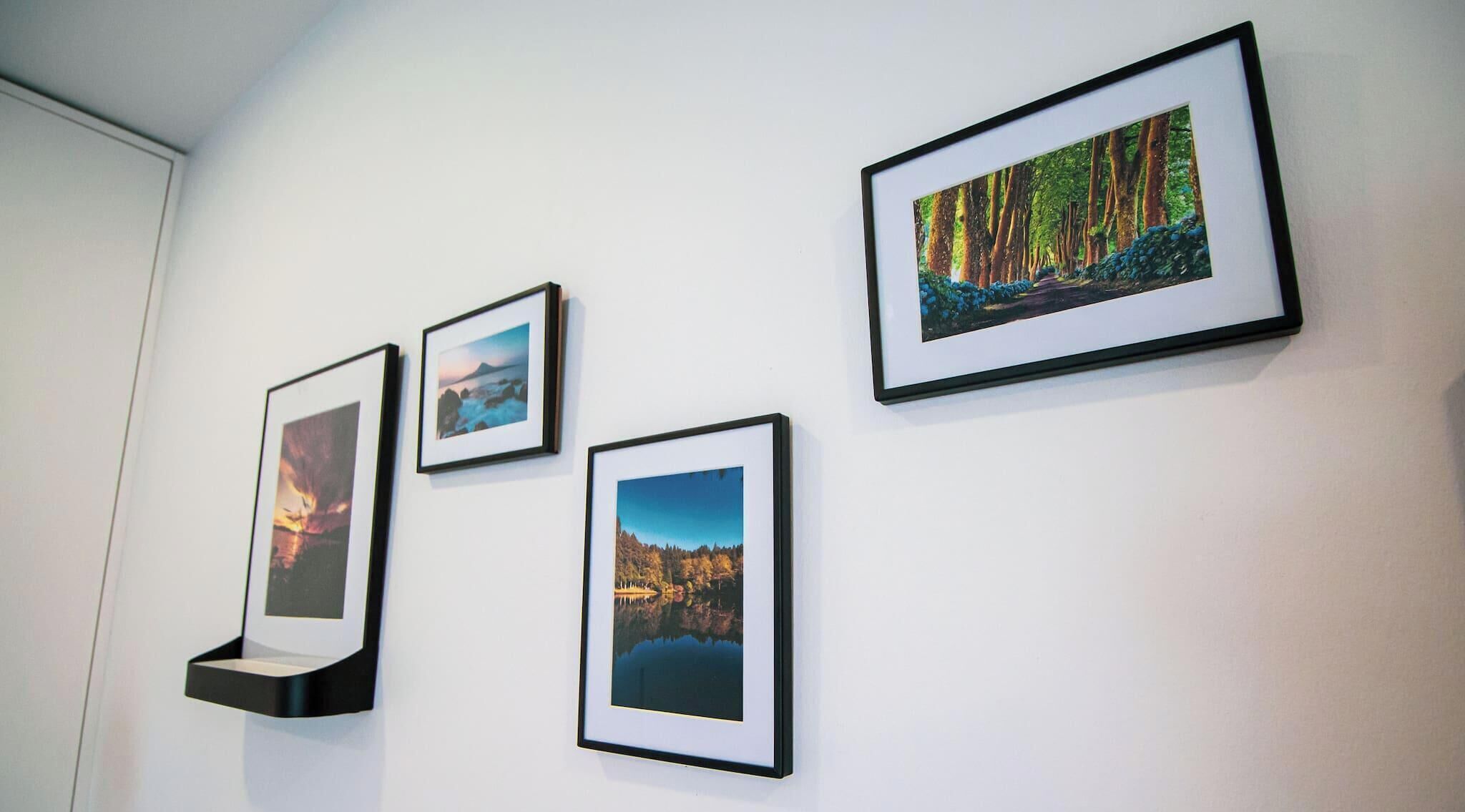 Eine Wand mit vier gerahmten Landschaftsfotografien.