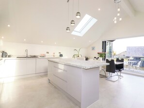 Una cocina moderna con una isla central, iluminación colgante y un tragaluz.