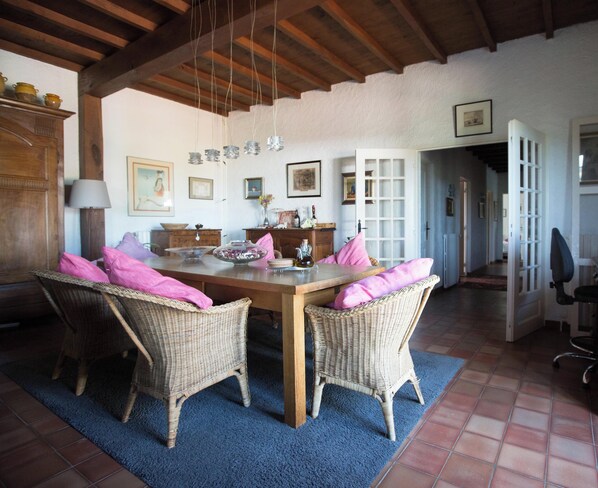 Un comedor con mesa de madera, sillas de mimbre y alfombra azul.