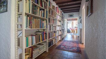 A library with bookshelves filled with books, a patterned rug on the floor, and a wooden ceiling.