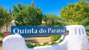 Un letrero con la inscripción 'Quinta do Paraíso', colocado sobre un banco blanco con respaldo curvo.