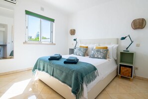 A bedroom with a bed, a nightstand, a lamp, a window, and a wall-mounted basket. - C59 Quinta do Paraiso -  Perfect Algarve escape with private garden and terraces (Carvoeiro)