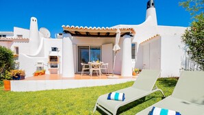 Una villa moderna con un patio, mobiliario exterior y zona de piscina.