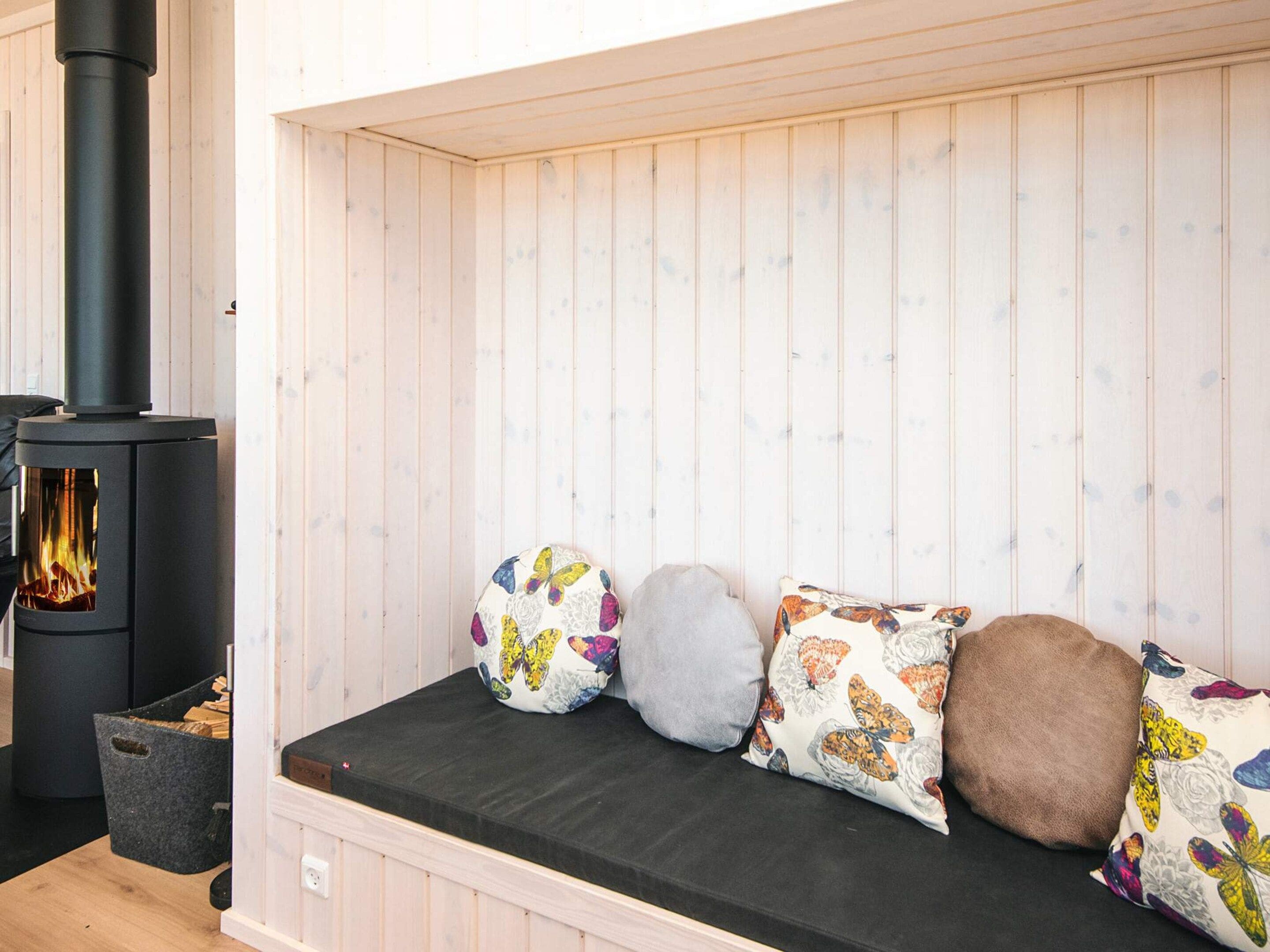 A room with a built-in fireplace, a bench with cushions, and a wooden wall.