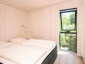 A bedroom with a bed, a window, and wooden walls. - 5 Star Holiday Home in Hejls (Hejls)