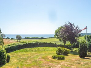 A golf course with a flag, trees, and a view of the sea. - 5 Star Holiday Home in Hejls (Hejls)