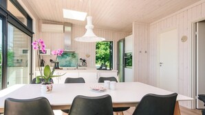 Eine moderne Küche mit weißen Schränken, einer großen Kochinsel und einem Essbereich mit weißem Tisch und schwarzen Stühlen.