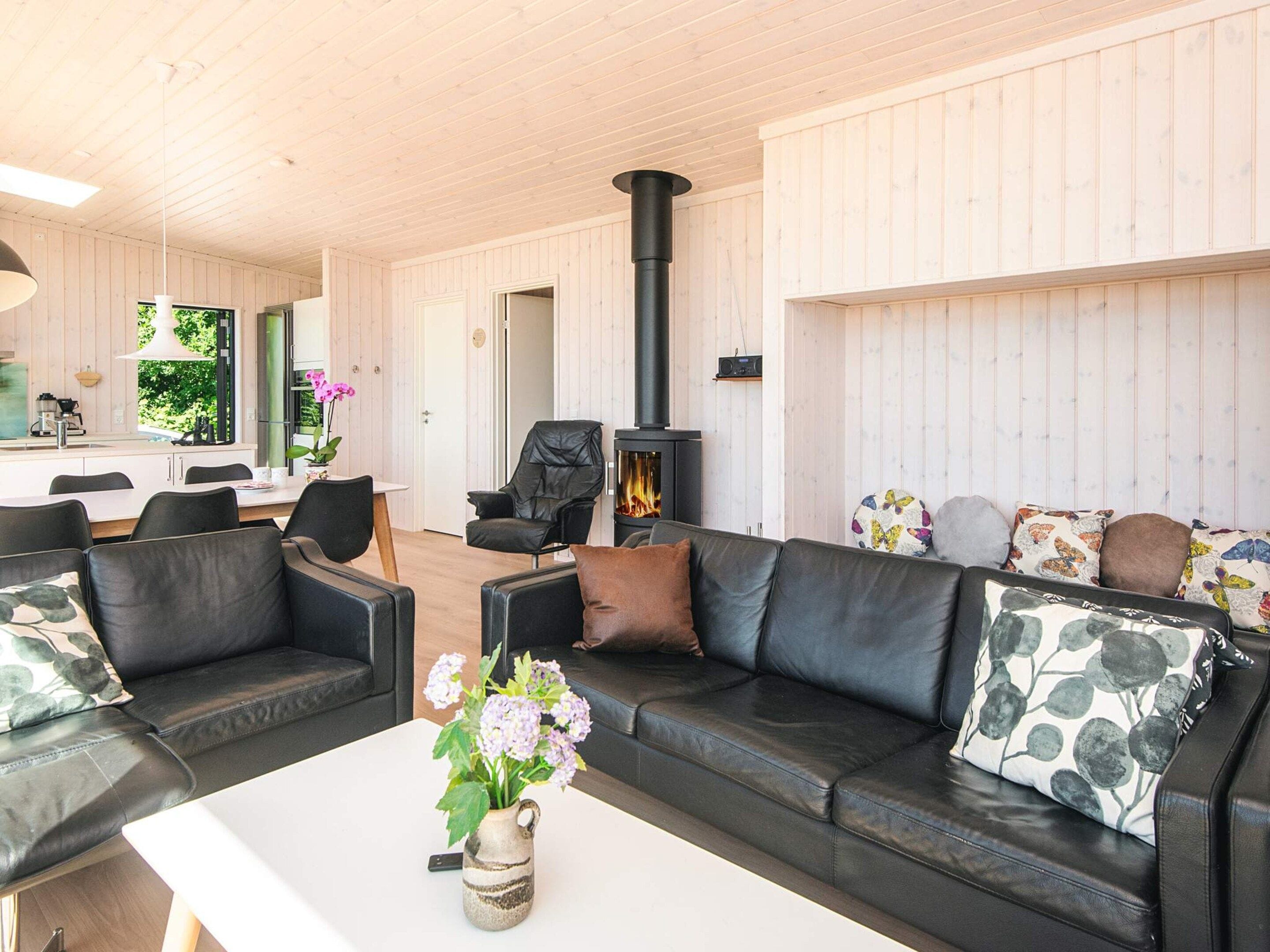 A modern living room with a fireplace, leather sofas, and a dining area.