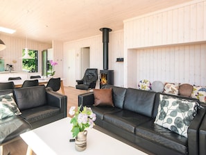 A modern living room with a fireplace, leather sofas, and a dining area. - 5 Star Holiday Home in Hejls (Hejls)