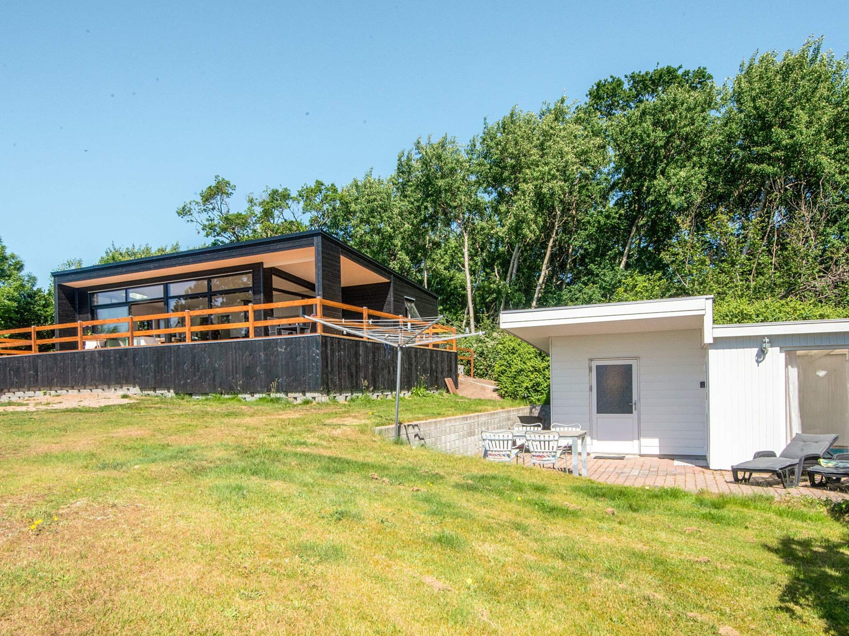 A modern two-story house with a balcony, a small attached garage, and a patio area with outdoor furniture.
