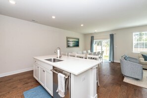 A modern kitchen with white cabinetry, a built-in sink, and a dining area with a table and chairs.