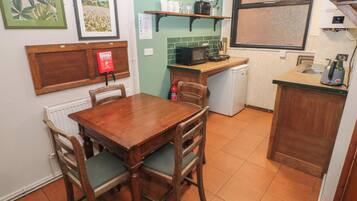 Una cocina compacta con una mesa de comedor, sillas, un microondas y un refrigerador pequeño.