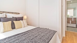 Un dormitorio con cama, almohadas, una lámpara de noche y vistas al baño.