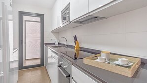 Una cocina moderna con un horno de acero inoxidable, una cafetera y una bandeja con tazas.