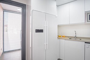 A modern kitchen with white cabinets, a stainless steel sink, and a microwave. - Cozy 2BR Apartment in Salamanca, Madrid (Madrid)