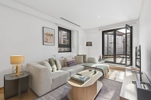 A modern living room with a sofa, coffee table, and a view of the city through large windows. - Bright & Elegant 2BR with Terrace (Madrid)
