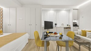 A modern hotel room with a bed, a dining table with chairs, a TV, and a kitchenette. - Cozy Studio by Colón & Salamanca District (Madrid)