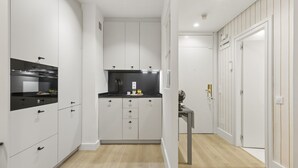 A modern kitchen with white cabinetry, a black countertop, and a built-in oven. - Cozy Studio by Colón & Salamanca District (Madrid)