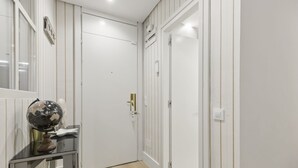 A hallway with white doors, a globe on a stand, and a light switch on the wall. - Cozy Studio by Colón & Salamanca District (Madrid)